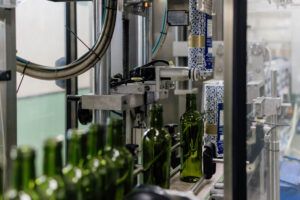línea de producción con botellas de vidrio hueco siendo inspeccionadas